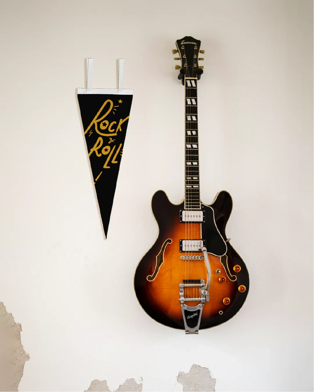 Electric guitar on a white wall with a 'Rock & Roll' pennant